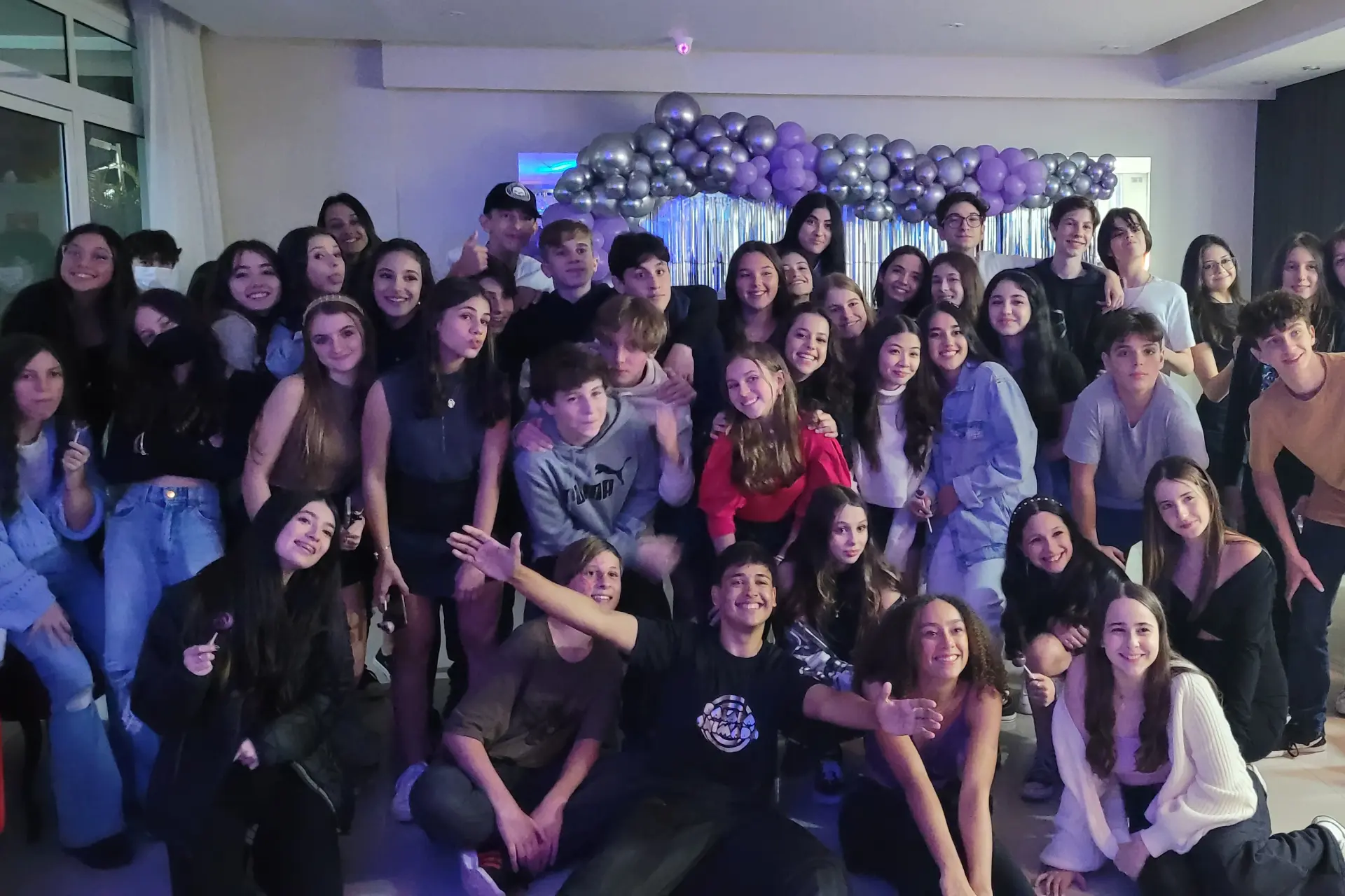 Convidados reunidos para foto em festa de 15 anos com balões e iluminação da Balada Animada.