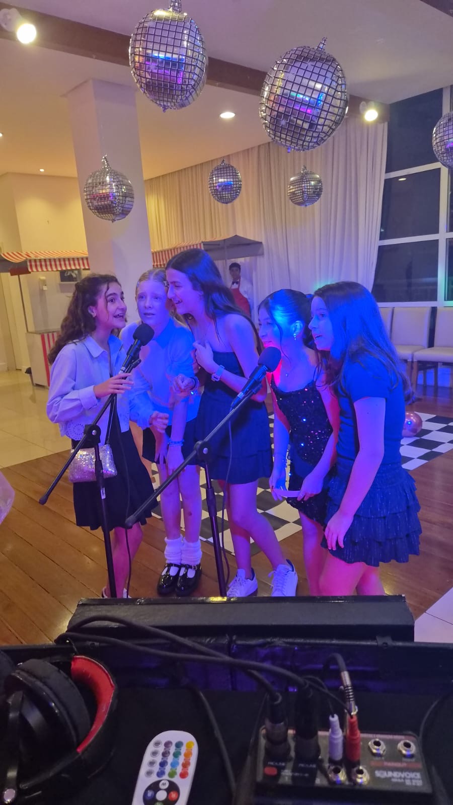 Grupo de meninas cantando no karaokê durante festa com globos de espelho