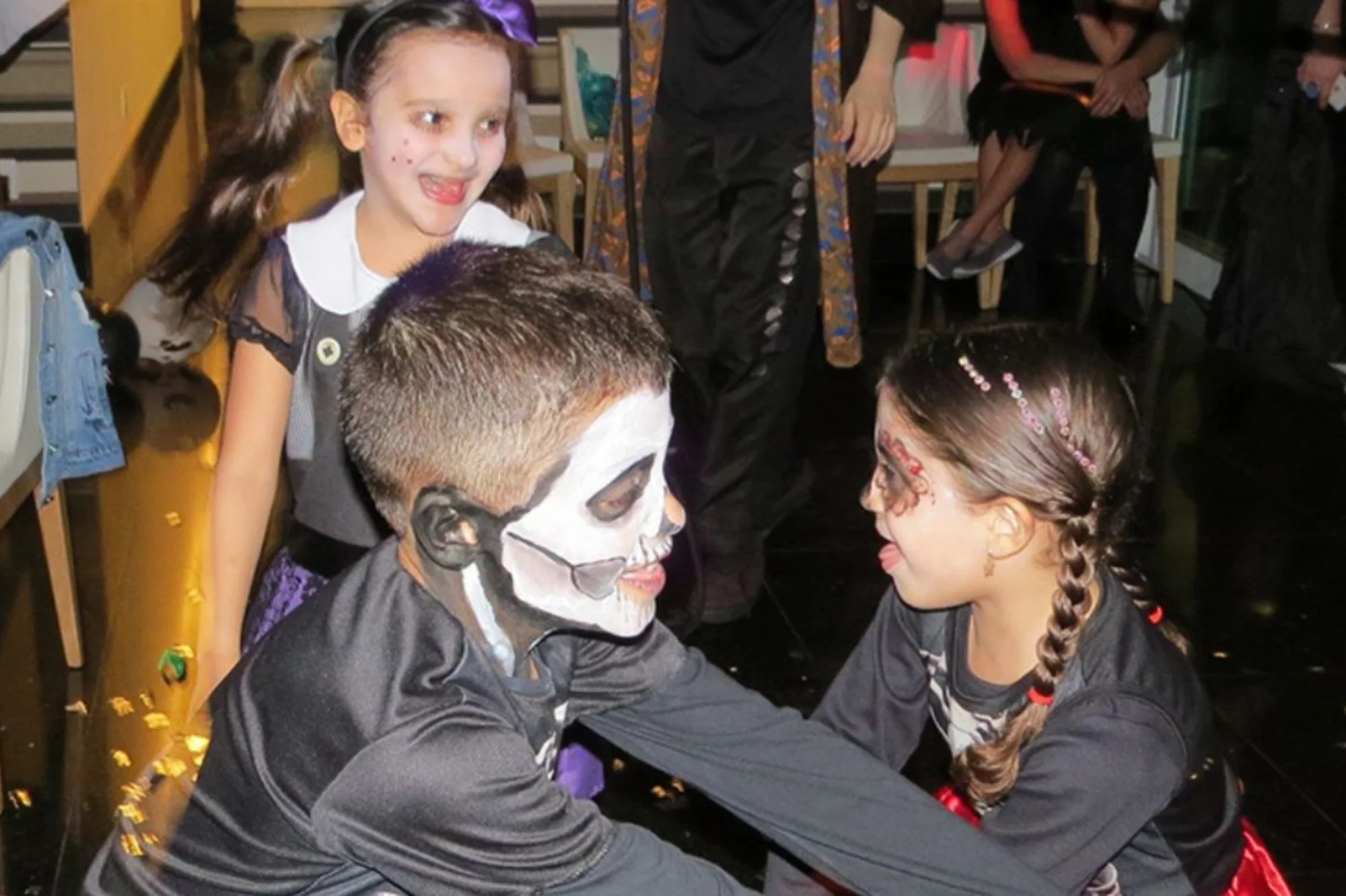 Crianças fantasiadas interagindo em uma festa de Halloween infantil