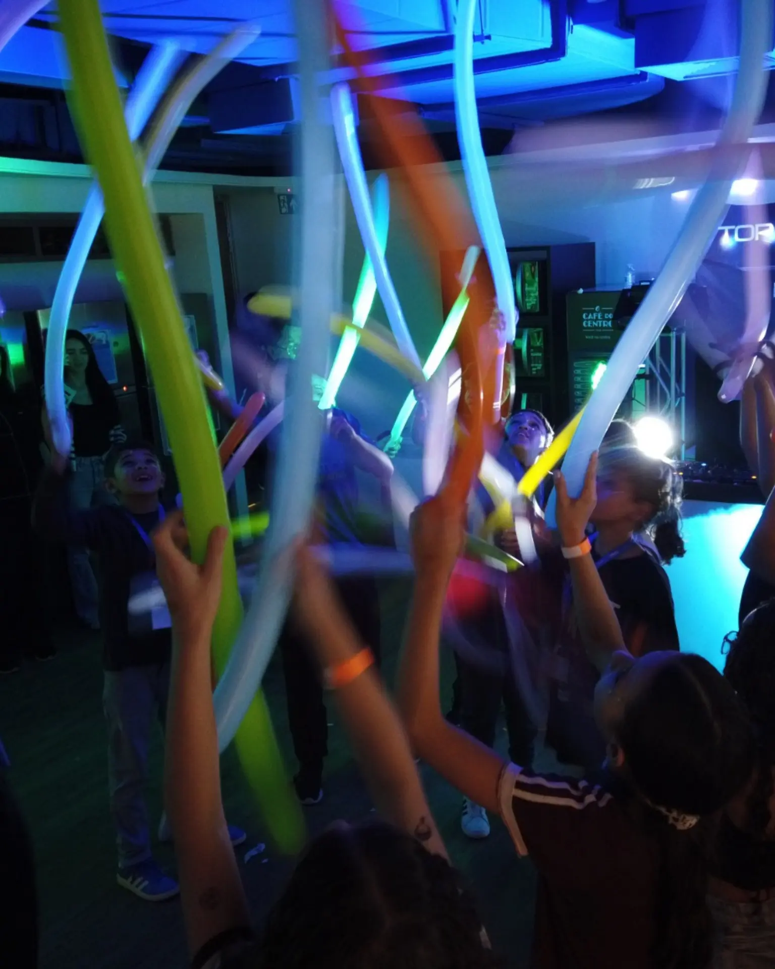 Formatura escolar com crianças levantando balões luminosos na pista.