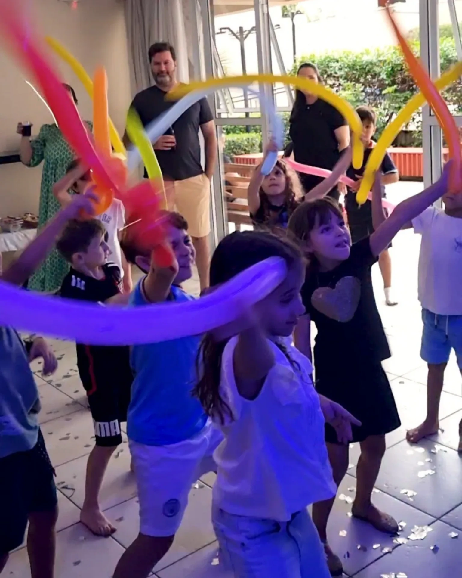 Crianças brincando com balões coloridos durante aniversário animado.