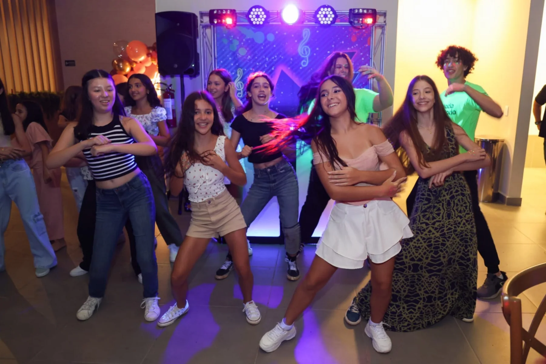 Adolescentes dançando em festa com DJ e iluminação da Balada Animada.