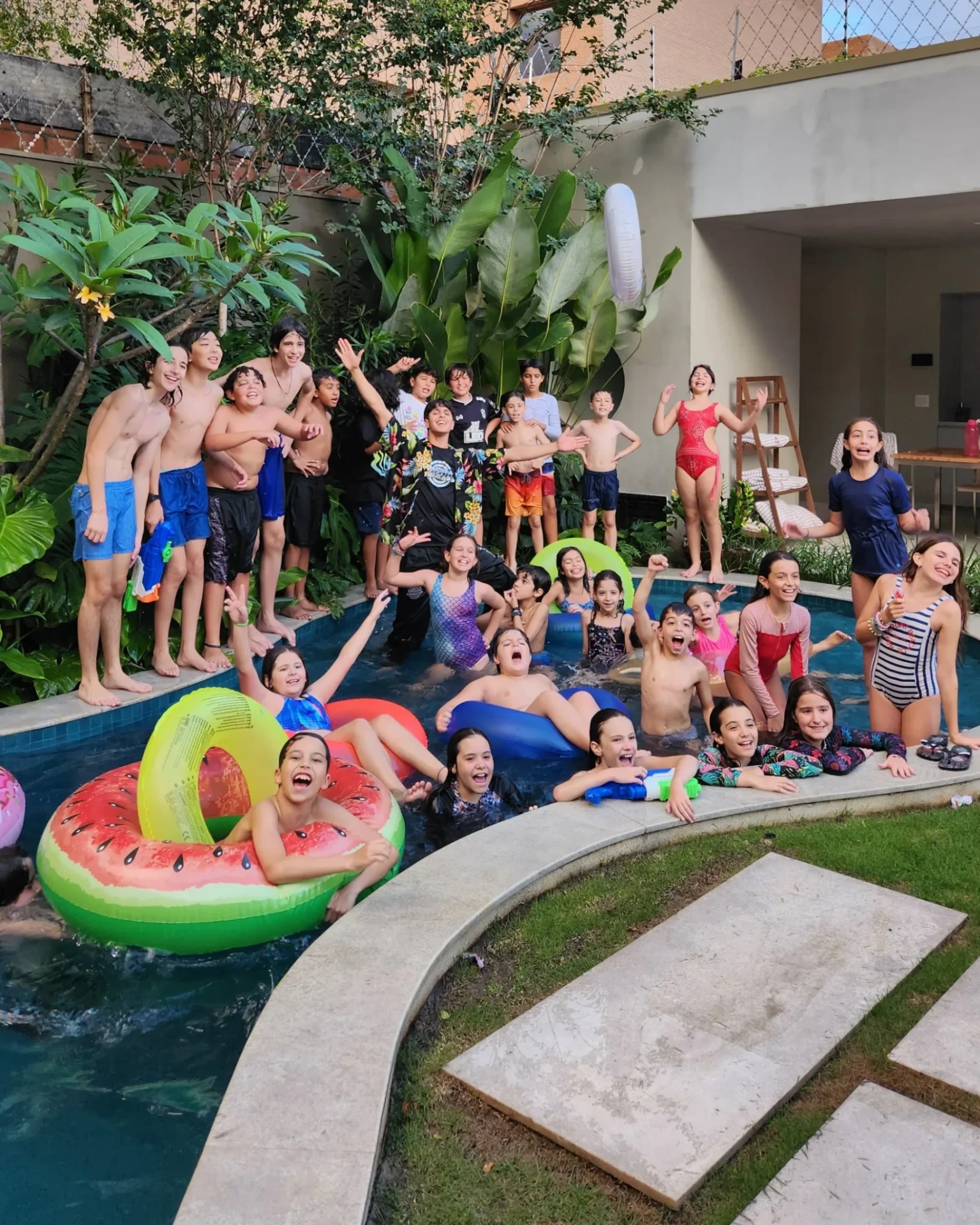 Grupo de crianças e adolescentes em pool party com boias coloridas