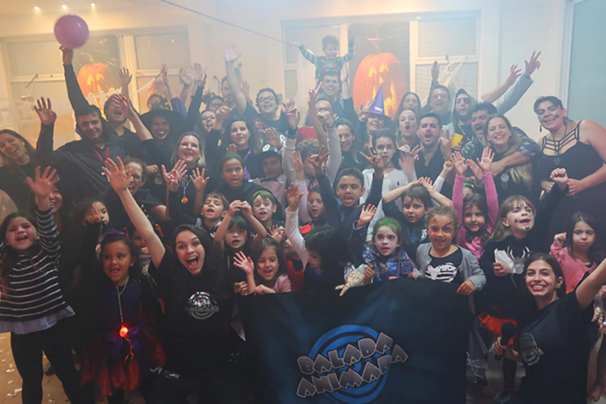 Grupo de crianças, adolescentes e adultos reunidos em uma festa de Halloween da Balada Animada