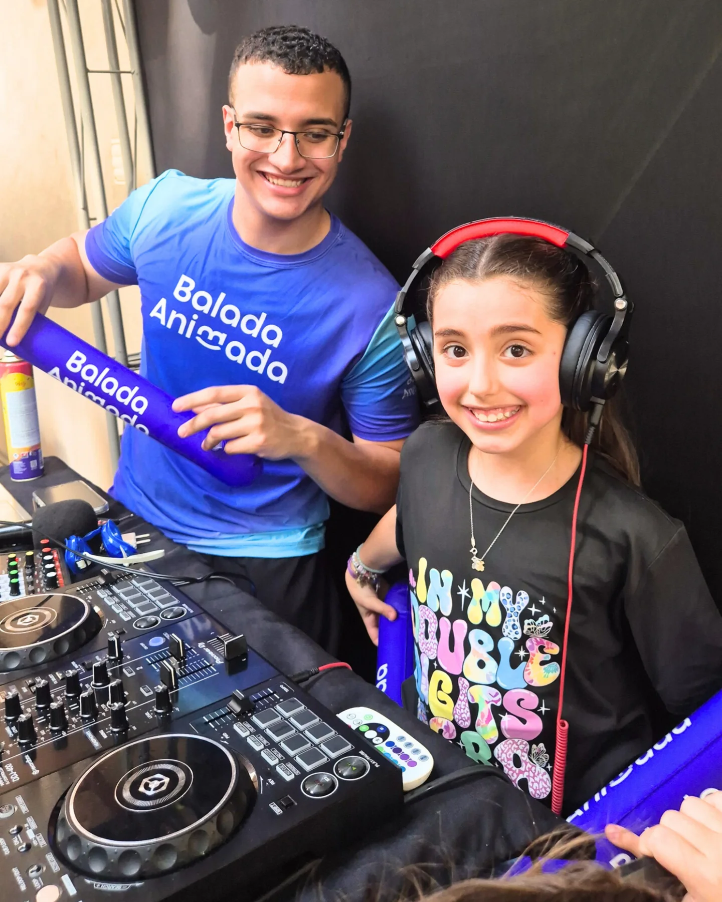 Aniversariante com fones na controladora de DJ ao lado da equipe