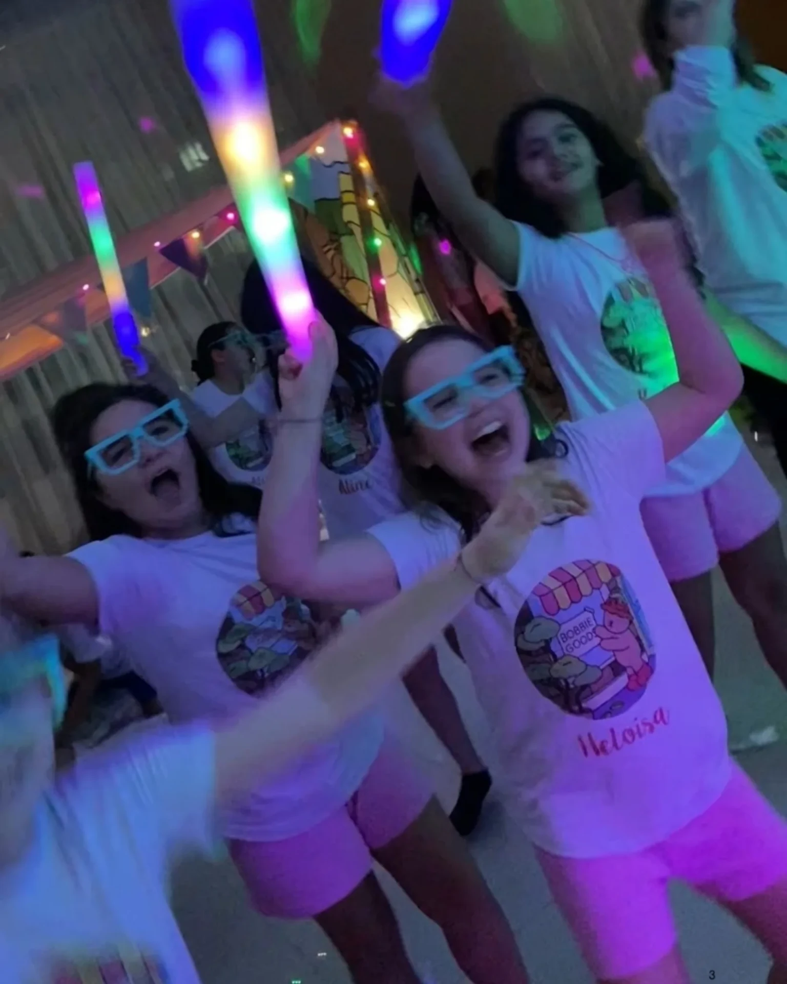 Meninas dançando com bastões de LED em festa da Balada Animada.
