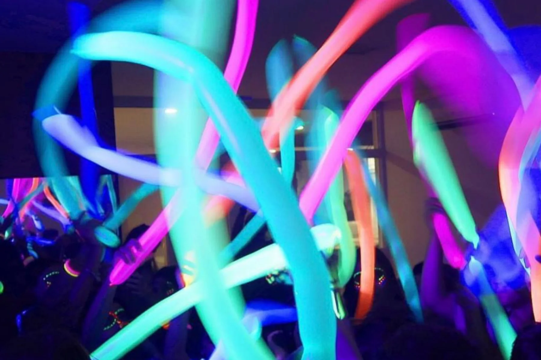 Balões neon coloridos erguidos na pista de dança durante a festa.